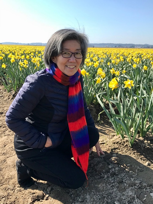 A woman kneeling next to a field of tulips