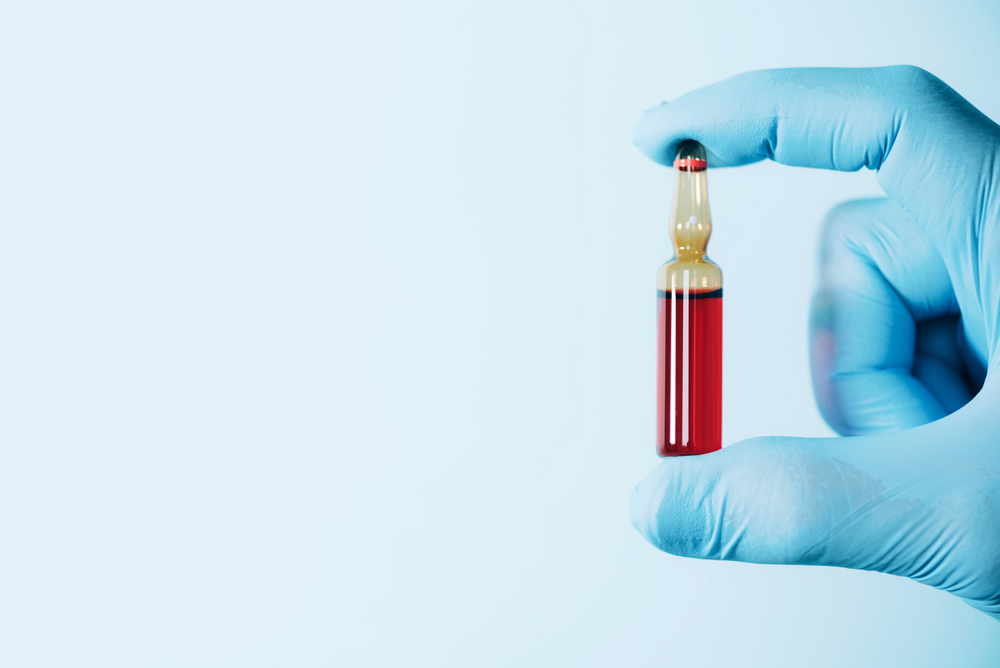 Gloved hand holding an ampule of medication